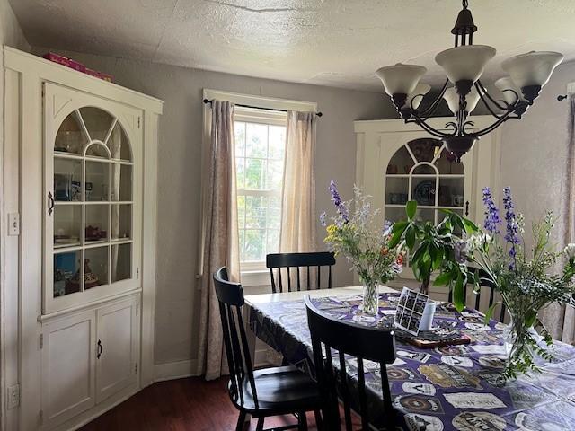 dining room featuring a textured ceiling, dark hardwood / wood-style floors, and a notable chandelier