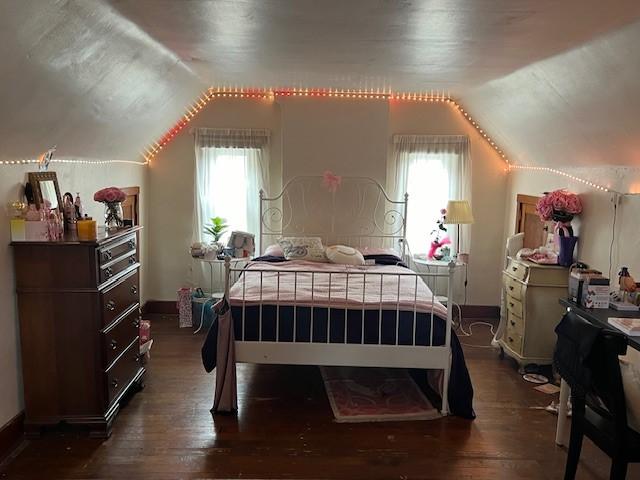 bedroom featuring multiple windows, dark wood-type flooring, and lofted ceiling