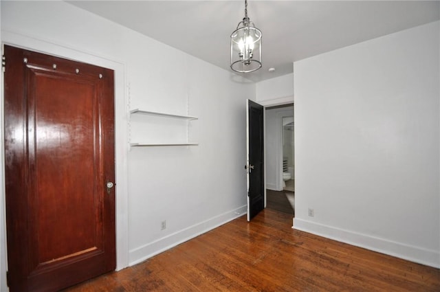 empty room featuring dark hardwood / wood-style flooring and a notable chandelier