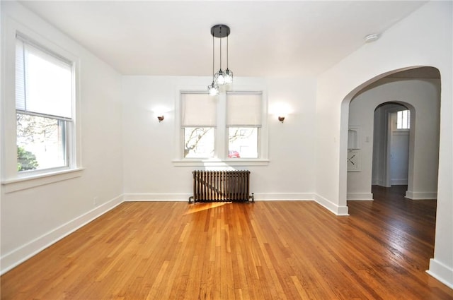 spare room featuring wood-type flooring and radiator