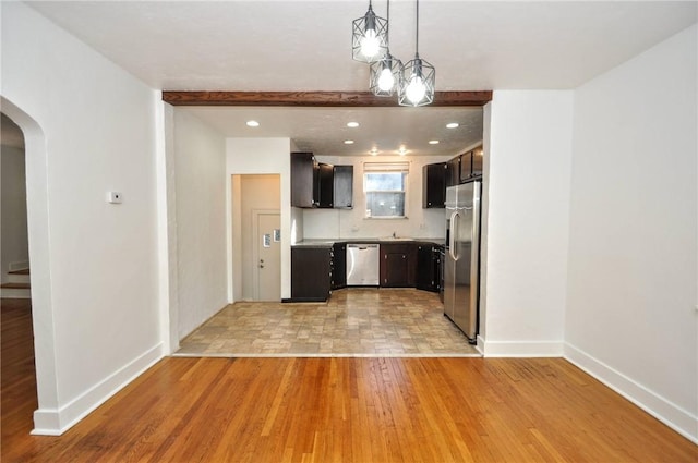 kitchen with beamed ceiling, pendant lighting, light wood-type flooring, and stainless steel appliances