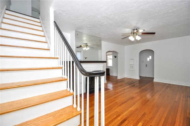 stairs featuring wood-type flooring, a textured ceiling, and ceiling fan