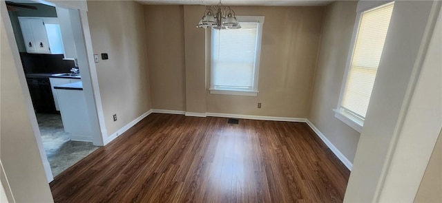 unfurnished dining area featuring dark hardwood / wood-style flooring and a notable chandelier