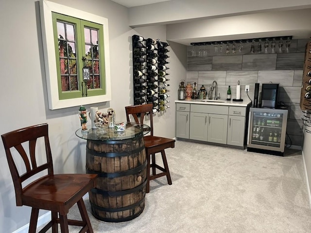 bar featuring sink, light colored carpet, and beverage cooler