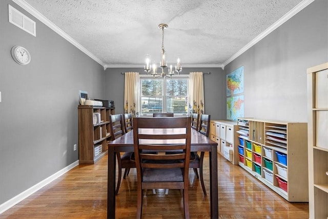 dining area featuring a textured ceiling, a notable chandelier, light wood-type flooring, and crown molding