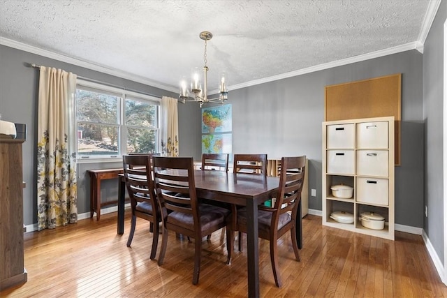 dining space featuring crown molding, a chandelier, a textured ceiling, and light wood-type flooring