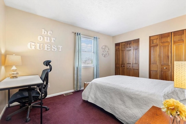 bedroom with multiple closets and dark colored carpet