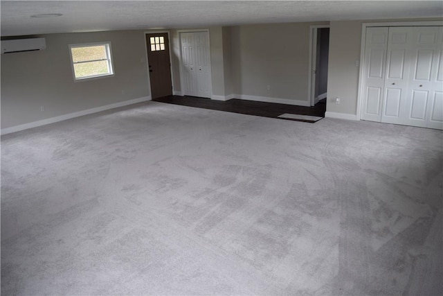 empty room featuring a wall mounted air conditioner, carpet floors, and a textured ceiling