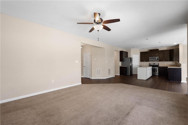 unfurnished living room with ceiling fan, sink, and dark wood-type flooring