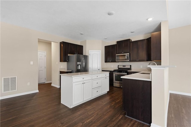 kitchen featuring dark wood-type flooring, sink, appliances with stainless steel finishes, dark brown cabinets, and a kitchen island