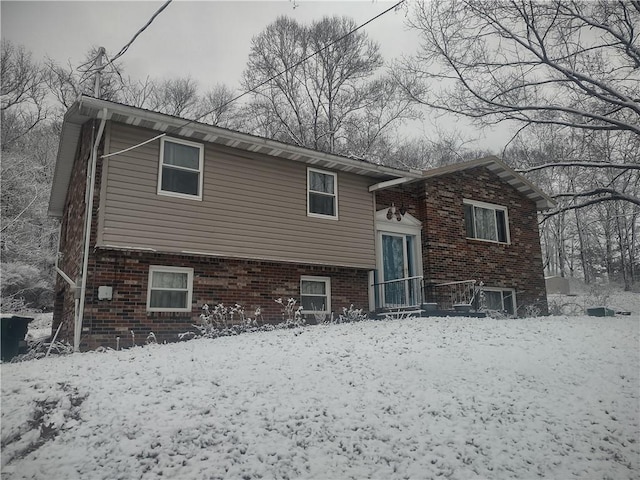 snow covered property featuring brick siding