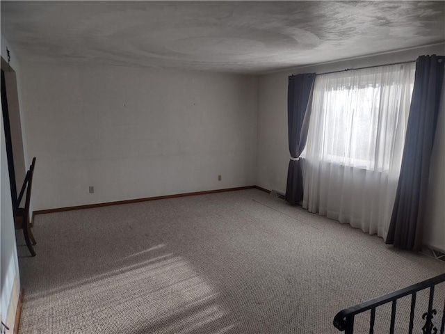 empty room featuring carpet and baseboards