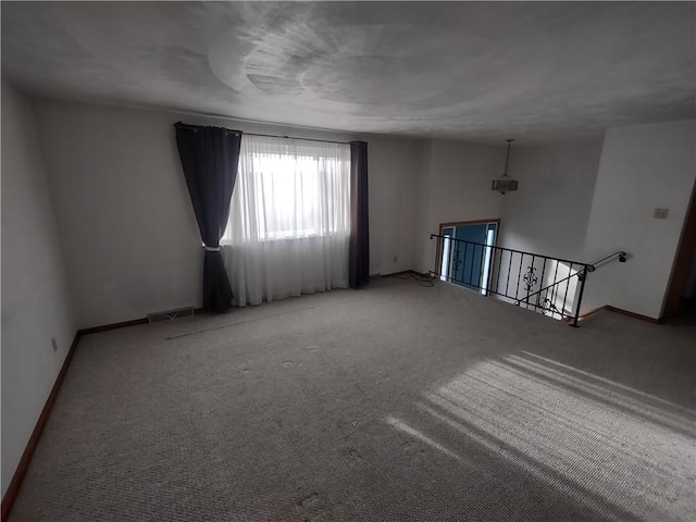 carpeted empty room with visible vents and baseboards