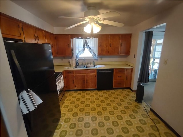 kitchen featuring brown cabinetry, light countertops, a sink, and black appliances