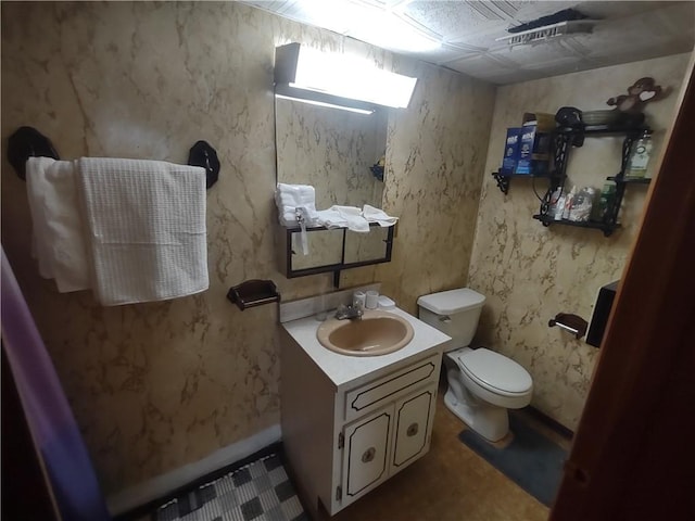 bathroom featuring vanity, toilet, and wallpapered walls