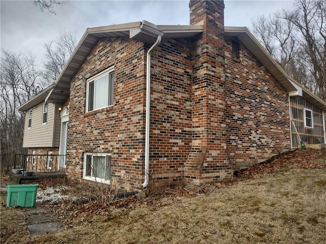 view of side of property featuring brick siding, a chimney, and a lawn