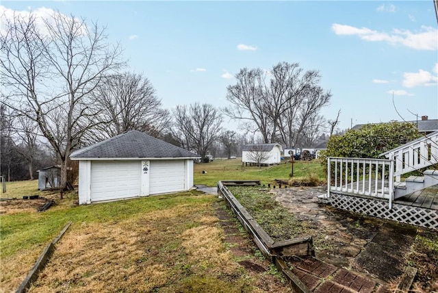 view of yard with an outbuilding, a garage, and a wooden deck