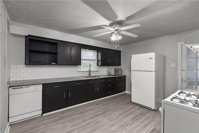 kitchen with backsplash, light stone counters, white appliances, sink, and light hardwood / wood-style floors