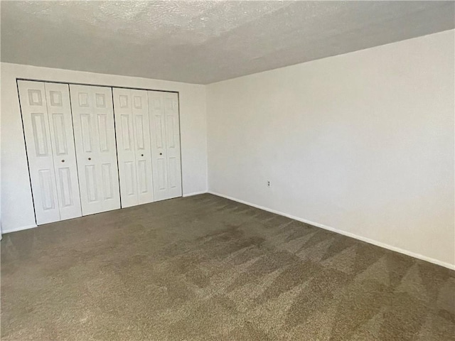 unfurnished bedroom featuring dark carpet and a textured ceiling