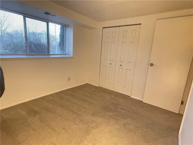 unfurnished bedroom with dark colored carpet and a closet