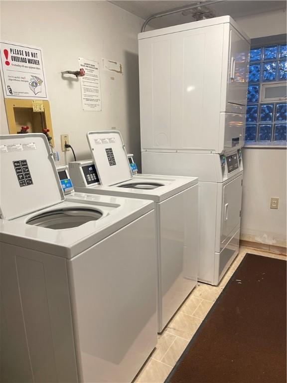 laundry area with light tile patterned floors, washing machine and dryer, and stacked washer and dryer