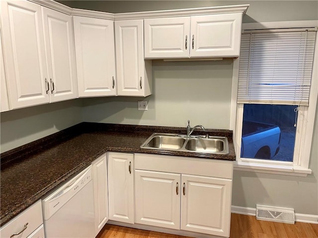 kitchen with dishwasher, dark stone counters, sink, light wood-type flooring, and white cabinetry