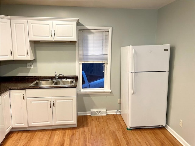 kitchen with white refrigerator, light wood-type flooring, white cabinetry, and sink