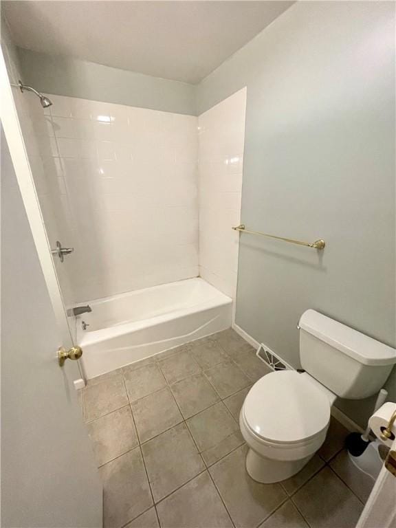 bathroom featuring tile patterned flooring, tiled shower / bath, and toilet