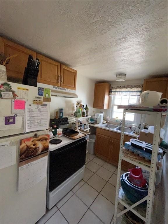 kitchen featuring sink, white appliances, a textured ceiling, and light tile patterned floors