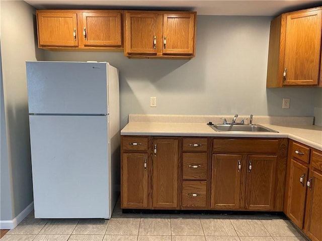 kitchen featuring light tile patterned floors, white fridge, and sink