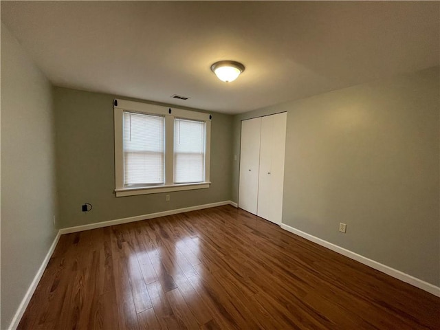 unfurnished bedroom with dark wood-type flooring and a closet