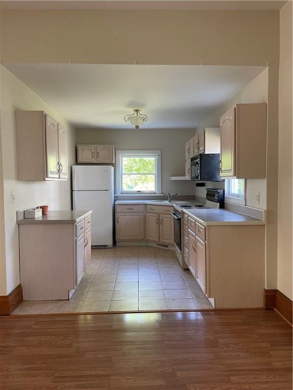 kitchen featuring electric range, white refrigerator, light brown cabinets, and light hardwood / wood-style flooring