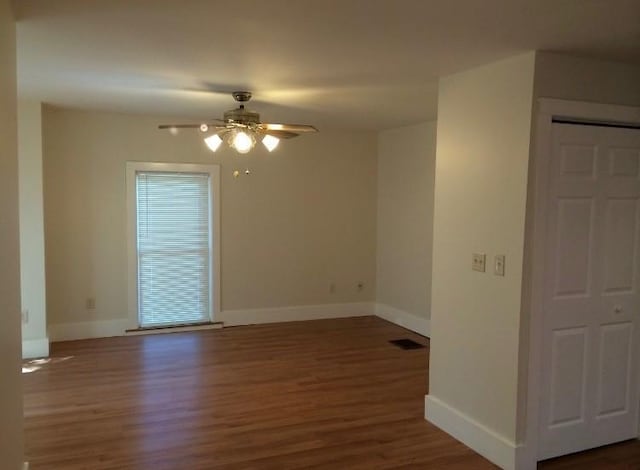 empty room with ceiling fan and dark hardwood / wood-style flooring