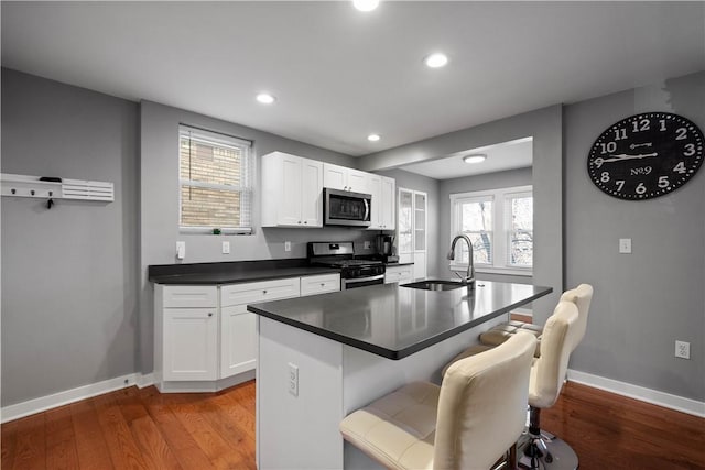 kitchen with sink, white cabinetry, stainless steel appliances, and light wood-type flooring