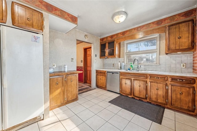 kitchen with light tile patterned floors, white refrigerator, stainless steel dishwasher, and sink