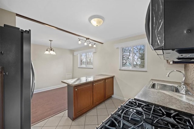 kitchen with stainless steel refrigerator, sink, a chandelier, pendant lighting, and light tile patterned floors