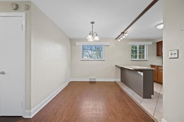 unfurnished dining area featuring light hardwood / wood-style floors and a chandelier