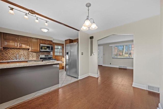 kitchen with a wealth of natural light, pendant lighting, light hardwood / wood-style floors, and appliances with stainless steel finishes