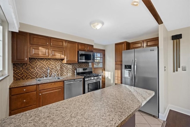 kitchen with sink, light hardwood / wood-style flooring, decorative backsplash, appliances with stainless steel finishes, and light stone counters