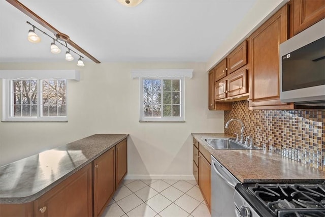 kitchen featuring sink, stainless steel appliances, backsplash, dark stone counters, and light tile patterned floors