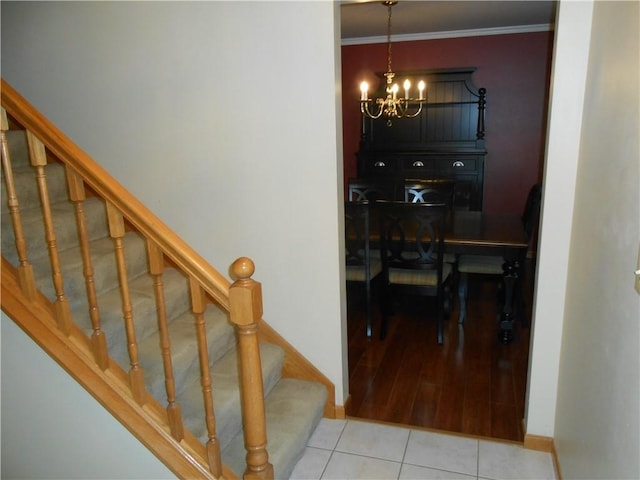 stairway featuring tile patterned floors, a chandelier, and ornamental molding