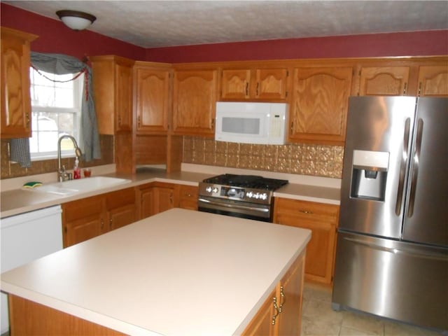 kitchen with a center island, sink, light tile patterned floors, a textured ceiling, and stainless steel appliances