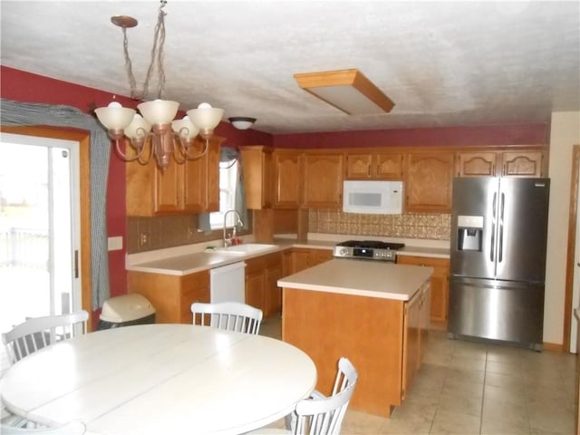 kitchen featuring white appliances, backsplash, a kitchen island, and sink