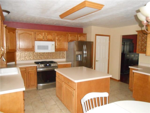 kitchen featuring sink, stainless steel appliances, light tile patterned floors, backsplash, and a kitchen island