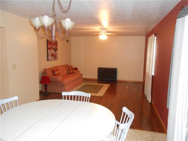 dining area featuring hardwood / wood-style floors, ceiling fan with notable chandelier, and a textured ceiling