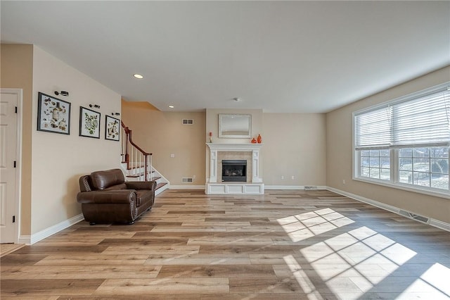 living room featuring a tile fireplace and light hardwood / wood-style flooring