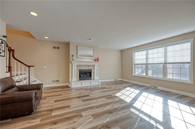 living room featuring a tile fireplace and light wood-type flooring