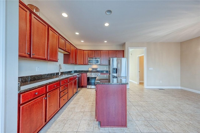 kitchen with stainless steel appliances, sink, light tile patterned floors, dark stone countertops, and a center island