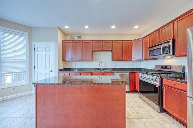 kitchen featuring a center island, light tile patterned floors, stainless steel appliances, and dark stone counters