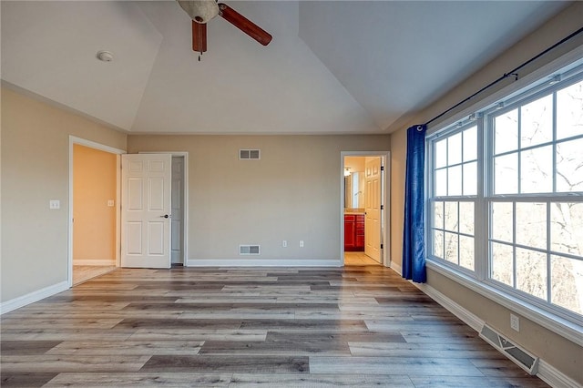 unfurnished bedroom with lofted ceiling, connected bathroom, and multiple windows